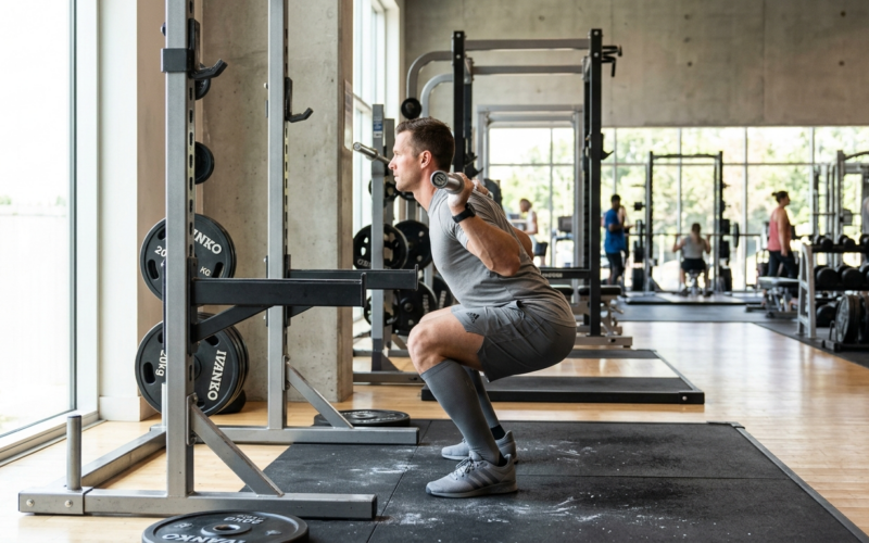 Persoon voert krachttraining uit met halter in een sportschool met natuurlijk licht.